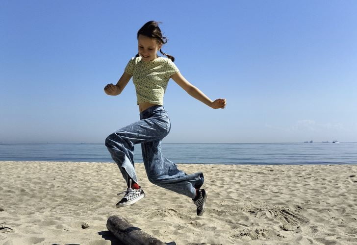 dziewczynka skacze na plazy w słoncu reja24